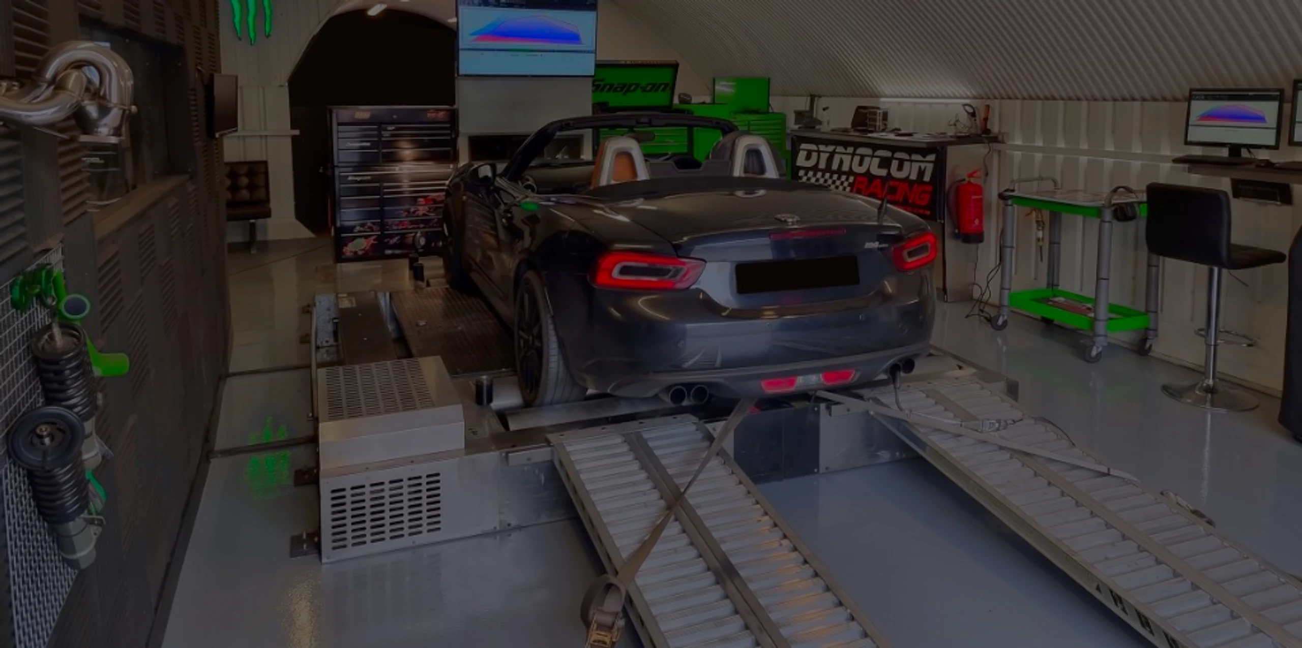 Abarth 124 Spider 1.4 Turbo Remap Bournemouth Poole Dorset | 24Tuning Black Abarth 124 Spider front three-quarter on Dynocom rolling road dyno with garage door open at 24Tuning Bournemouth Dorset workshop for Stage 1 ECU remapping