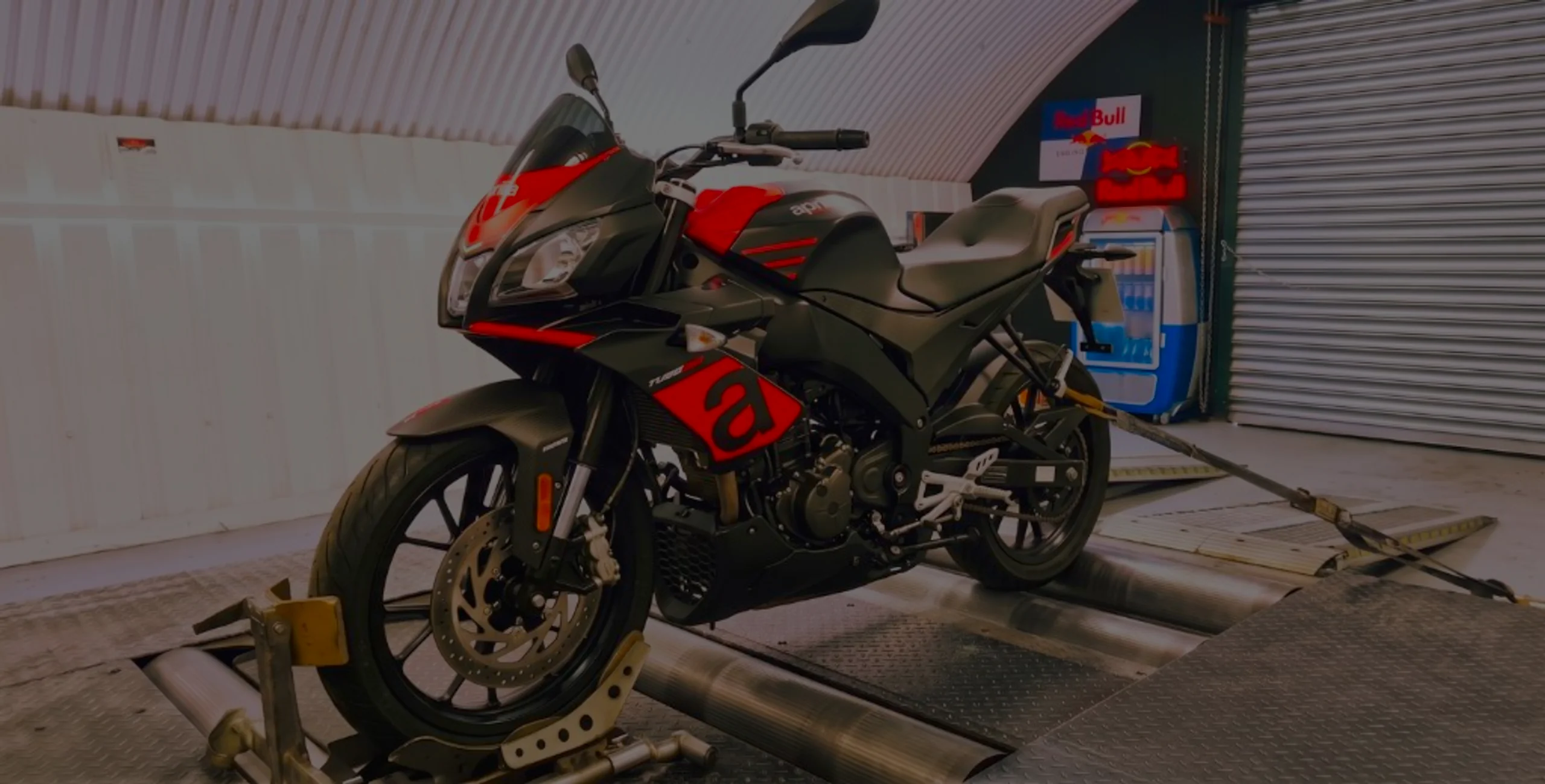 Black and red Aprilia Tuono 125 front three-quarter on motorcycle rolling road dyno with TUONO 125 fairing lettering at 24Tuning Bournemouth Dorset workshop for Stage 1 ECU remapping