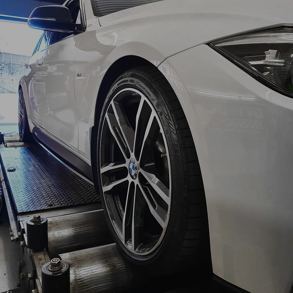 White BMW 3 Series F30 front wheel on Dynocom rolling road rollers during remap testing at 24Tuning Bournemouth Dorset