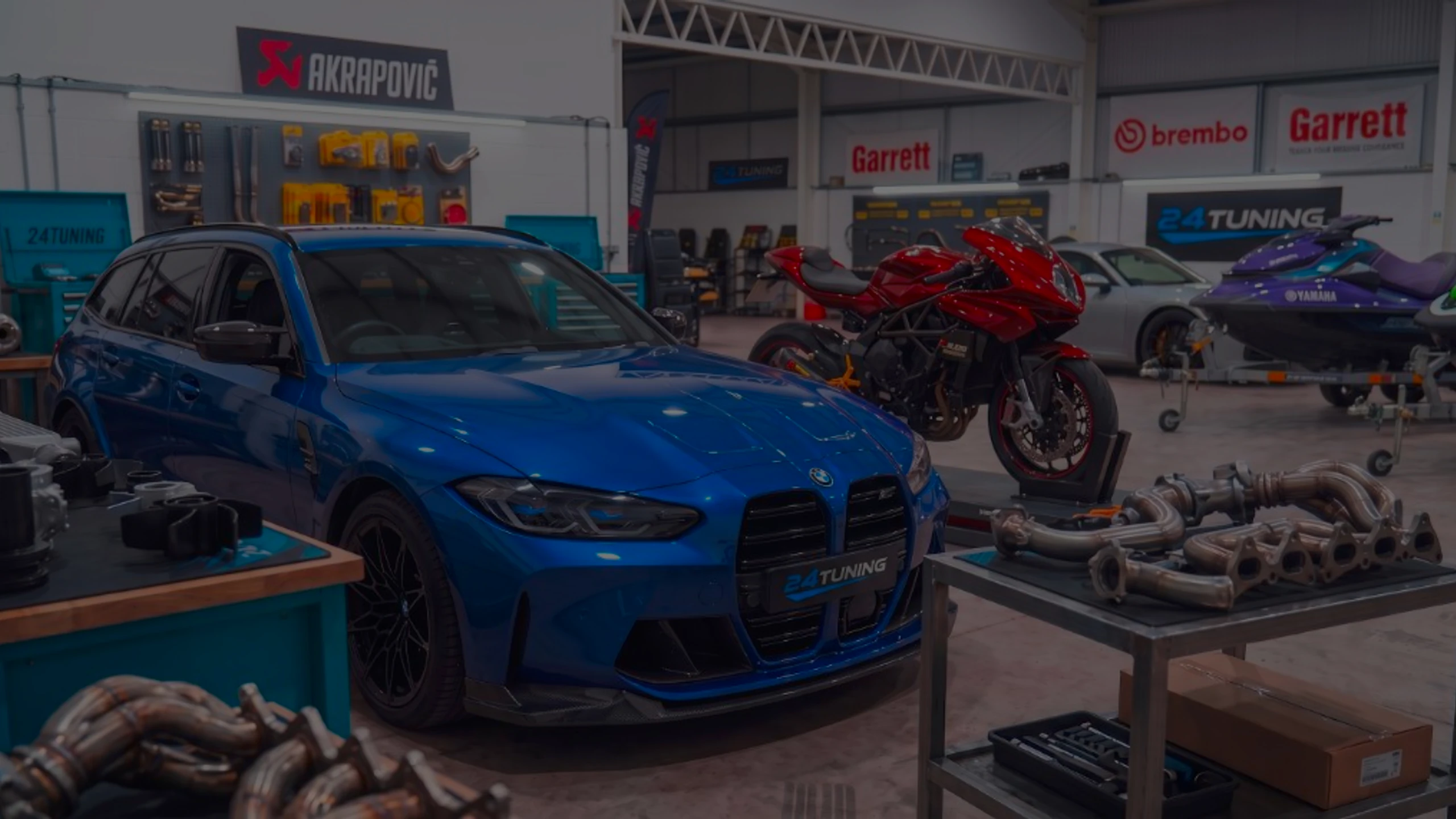 Blue BMW in the 24Tuning Bournemouth Dorset workshop with motorcycle, Porsche and Yamaha jet ski for ECU remapping and chip tuning services