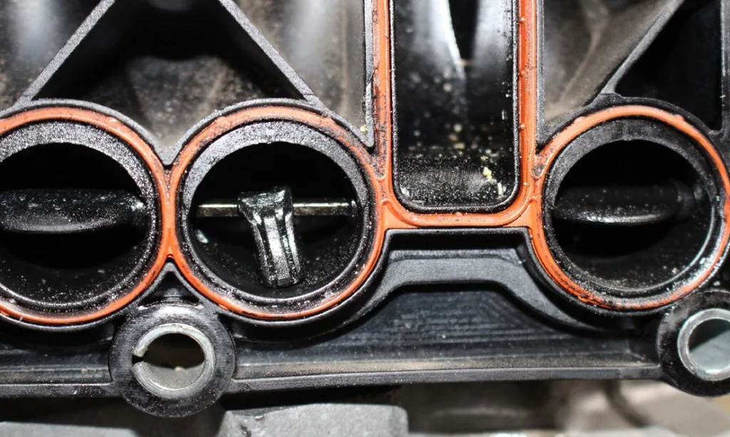 Broken swirl flap hanging in an intake manifold port with carbon buildup — Bournemouth Dorset