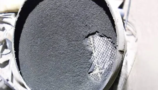 Clogged DPF end face covered in black soot with honeycomb exposed where soot broke away — Dorset