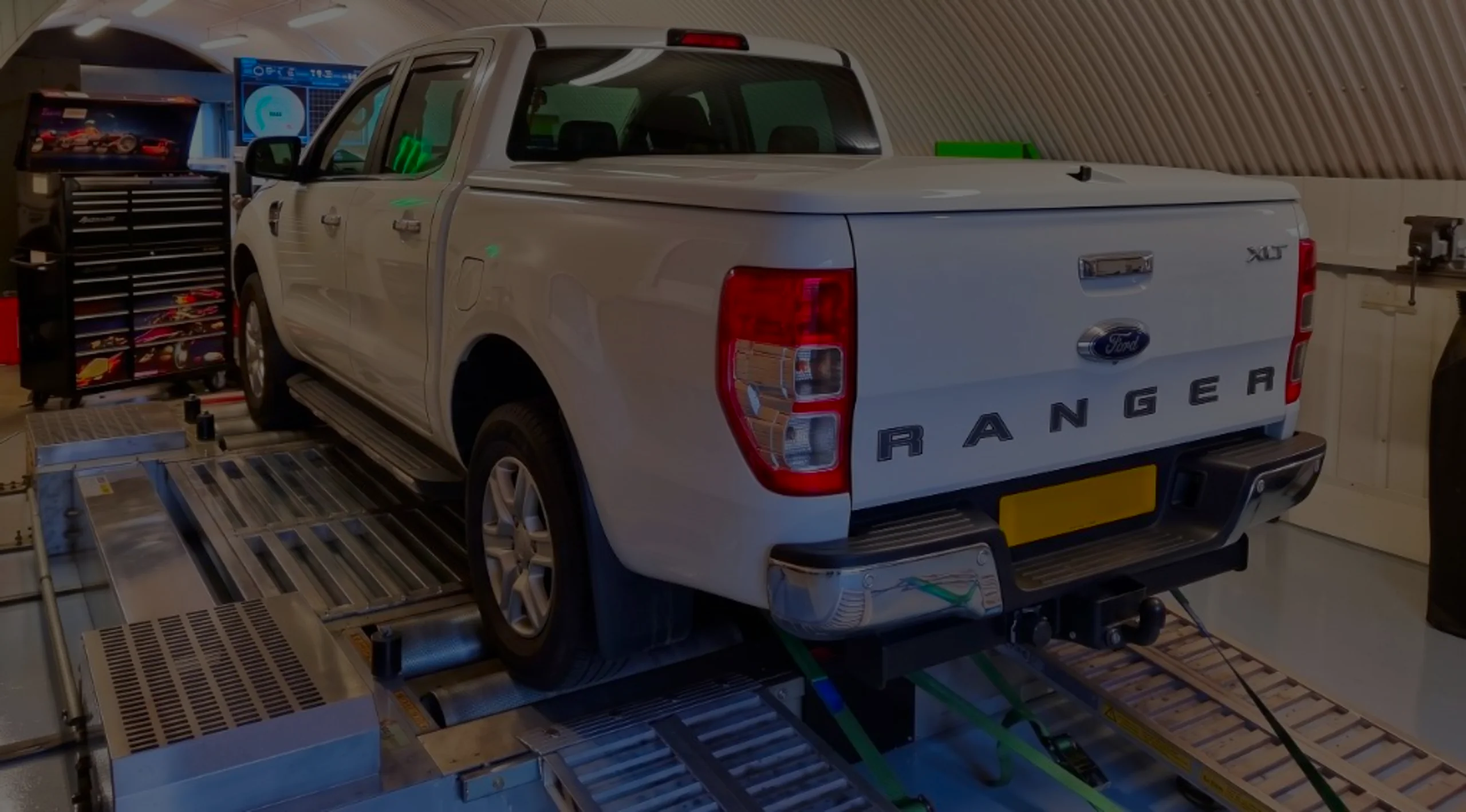 White Ford Ranger XLT rear three-quarter on rolling road dyno with RANGER tailgate lettering and green safety straps at 24Tuning Bournemouth Dorset workshop for Stage 1 ECU remapping