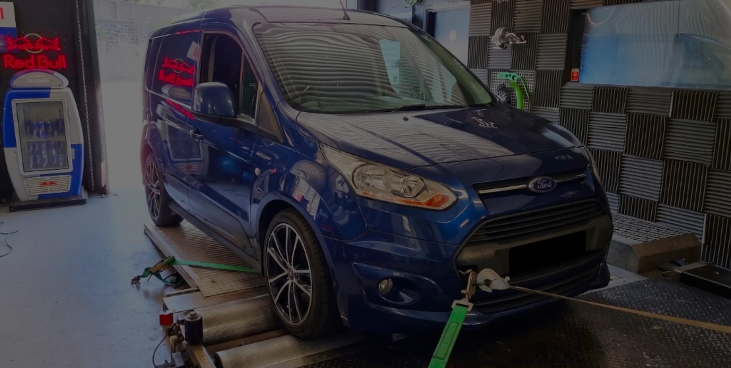 Dark blue Ford Transit Connect front three-quarter on rolling road dyno with green safety straps at 24Tuning Bournemouth Dorset workshop for Stage 1 ECU remapping