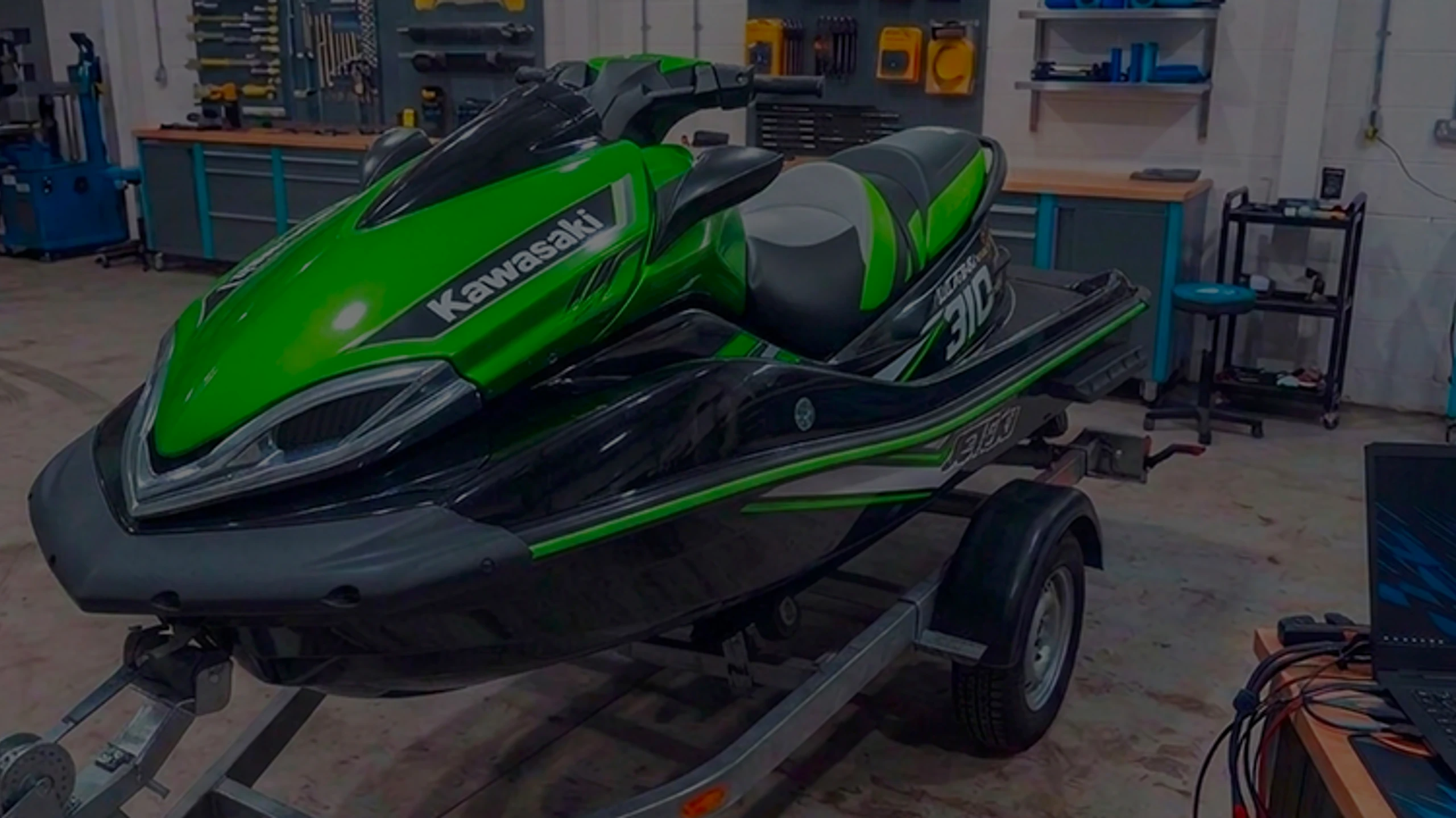 Green Kawasaki Ultra 310 jet ski on a trailer in the 24Tuning Bournemouth Dorset workshop with ECU remapping laptop for PWC tuning