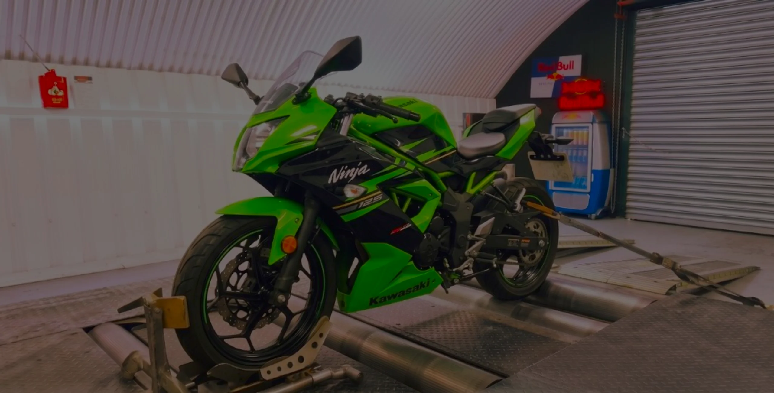 Kawasaki Ninja 125 Remap Bournemouth Poole Dorset | 24Tuning Lime green Kawasaki Ninja 125 front three-quarter on motorcycle rolling road dyno with Ninja fairing lettering at 24Tuning Bournemouth Dorset workshop for Stage 1 ECU remapping