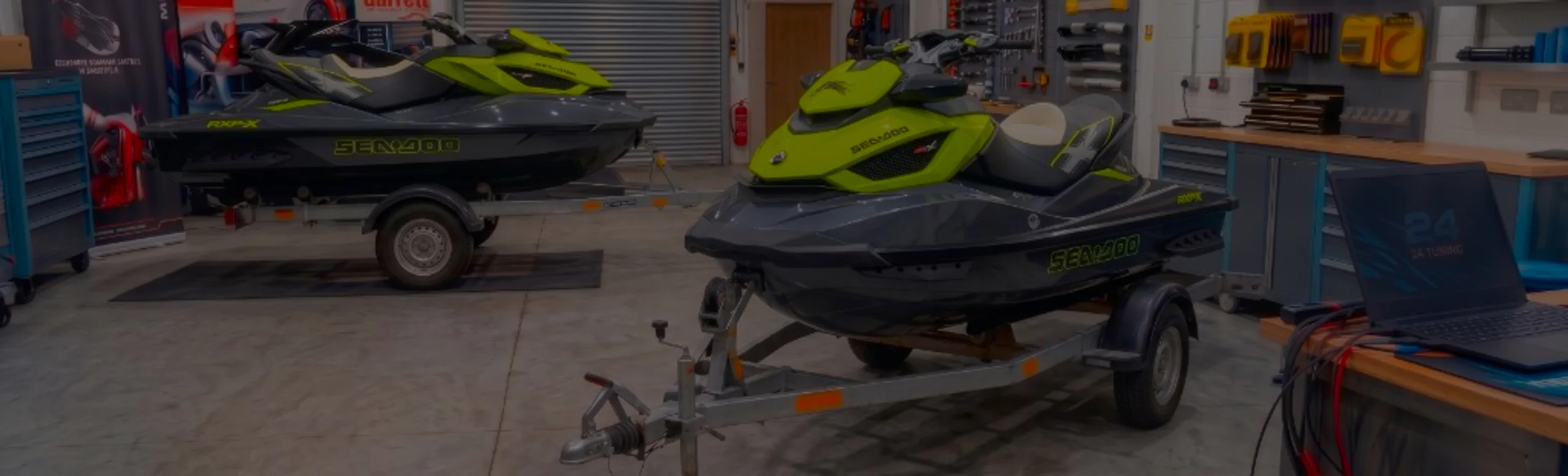 Grey and black Sea-Doo RXT jet skis on trailers in the 24Tuning Bournemouth Dorset workshop with ECU remapping laptop and tuning cables for Stage 1 jet-ski calibration