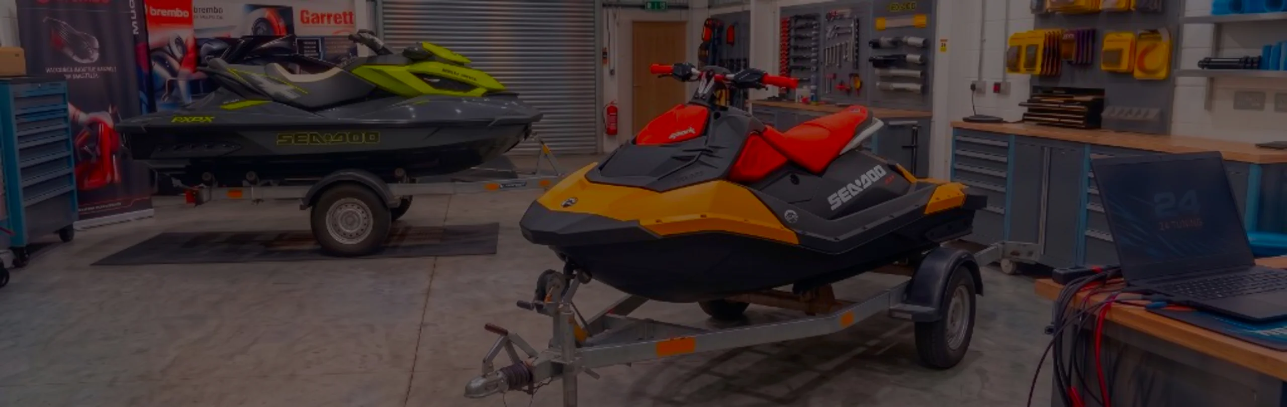 Black and orange Sea-Doo Spark Trixx jet ski on a trailer in the 24Tuning Bournemouth Dorset workshop with ECU remapping laptop and tuning cables for Stage 1 PWC calibration
